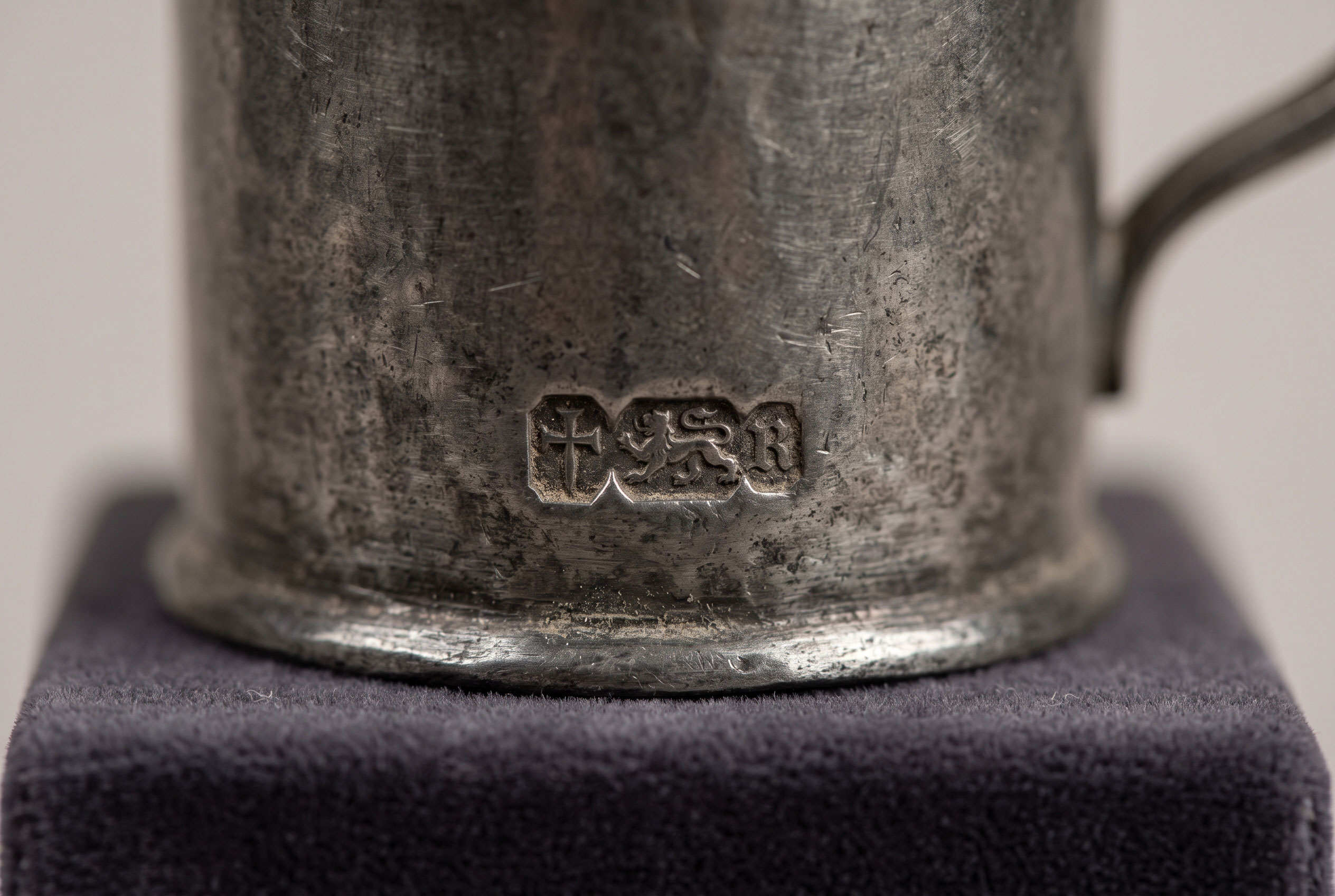 Close-up of a small stamped mark on a pewter object.